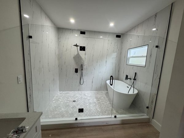 Paneles de cristal fijos con herrajes negros en un baño con bañera exenta