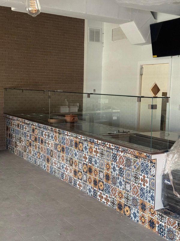 Panel de cristal sobre una barra con azulejos decorativos en un local