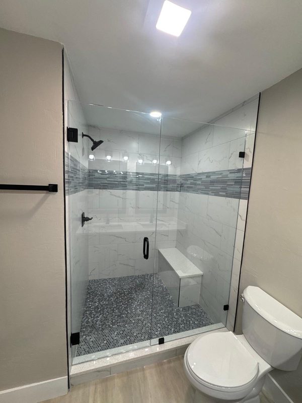 Mampara de cristal con puerta abatible, herrajes negros y banco interior